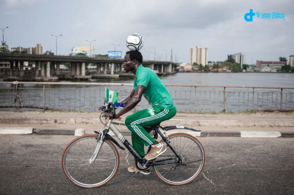 Harrison Chinedu balances a football on his head while riding a bicycle for a 103,6 km through the streets of Lagos on November 20, 2016.  Harrison Chinedu has set a new Guinness World Record for the greatest distanced travelled on a bicycle whilst balancing a football on the head. / AFP PHOTO / STEFAN HEUNIS
